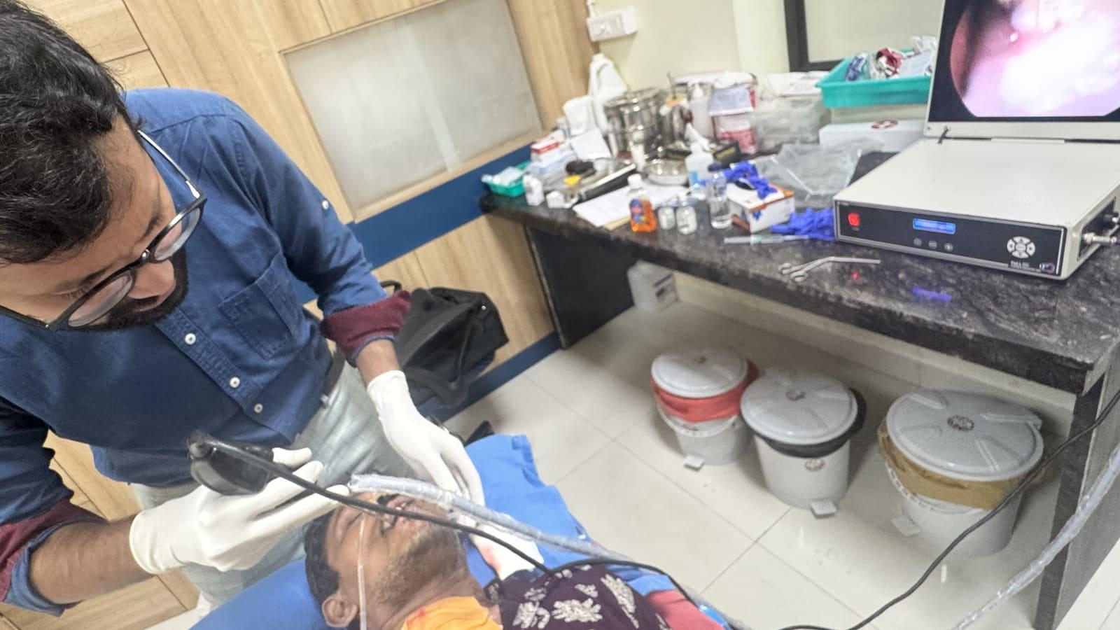 A clinician carrying out a procedure on a patient lying back, with a monitor beside them