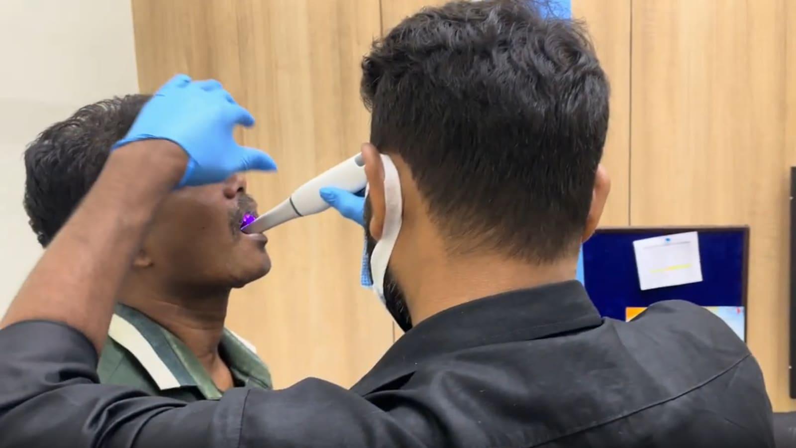 A clinician examining a patient's mouth with a handheld instrument